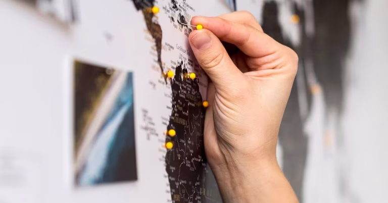 Hand adding a pin to world map with film lab pins